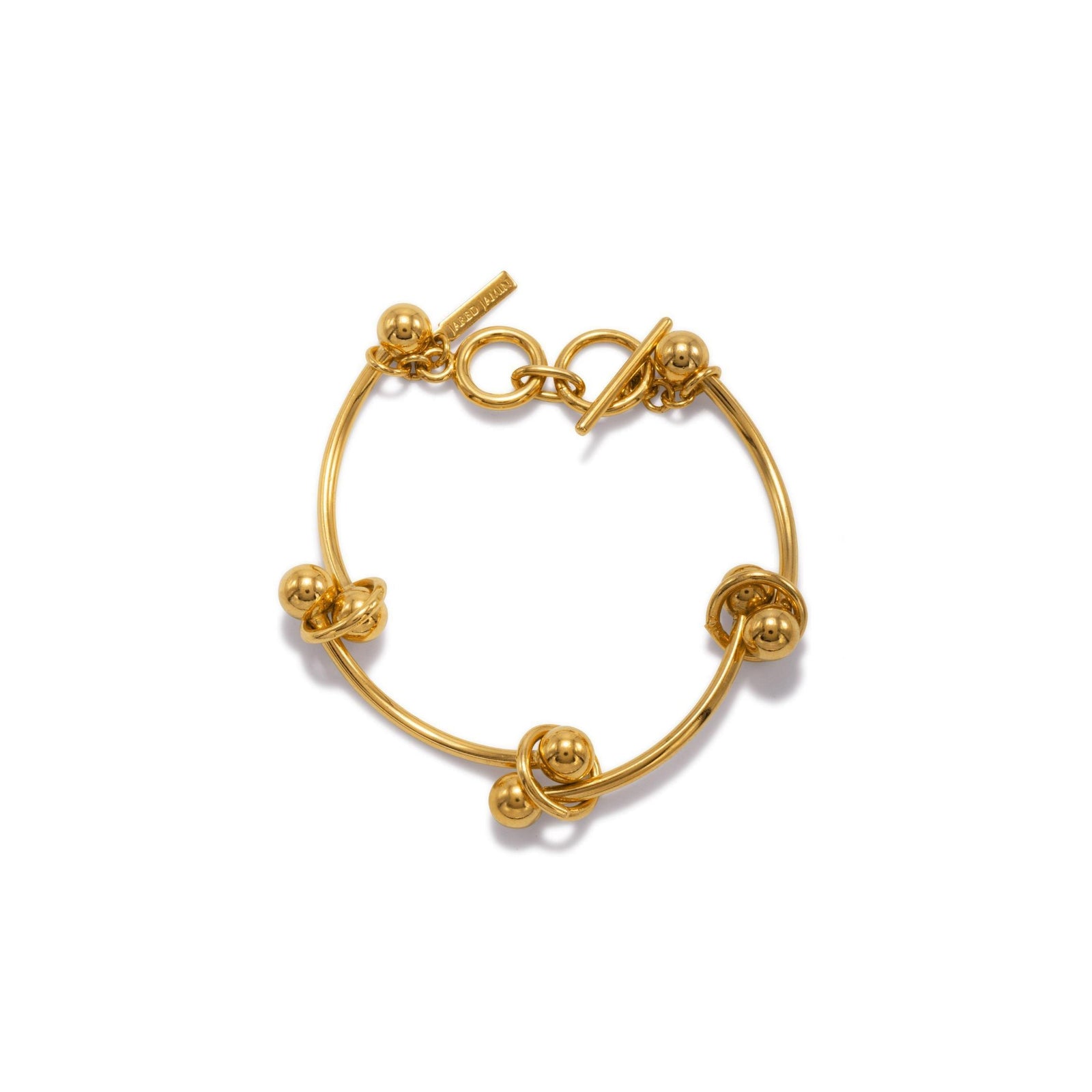 The Gold Smaller Orbita Nova Bracelet by JAREDJAMIN Jewelry Online features a minimalist 18K gold-plated circular band with four gold beads knotted in place, a toggle clasp, a rectangular tag, and a polished modern finish.