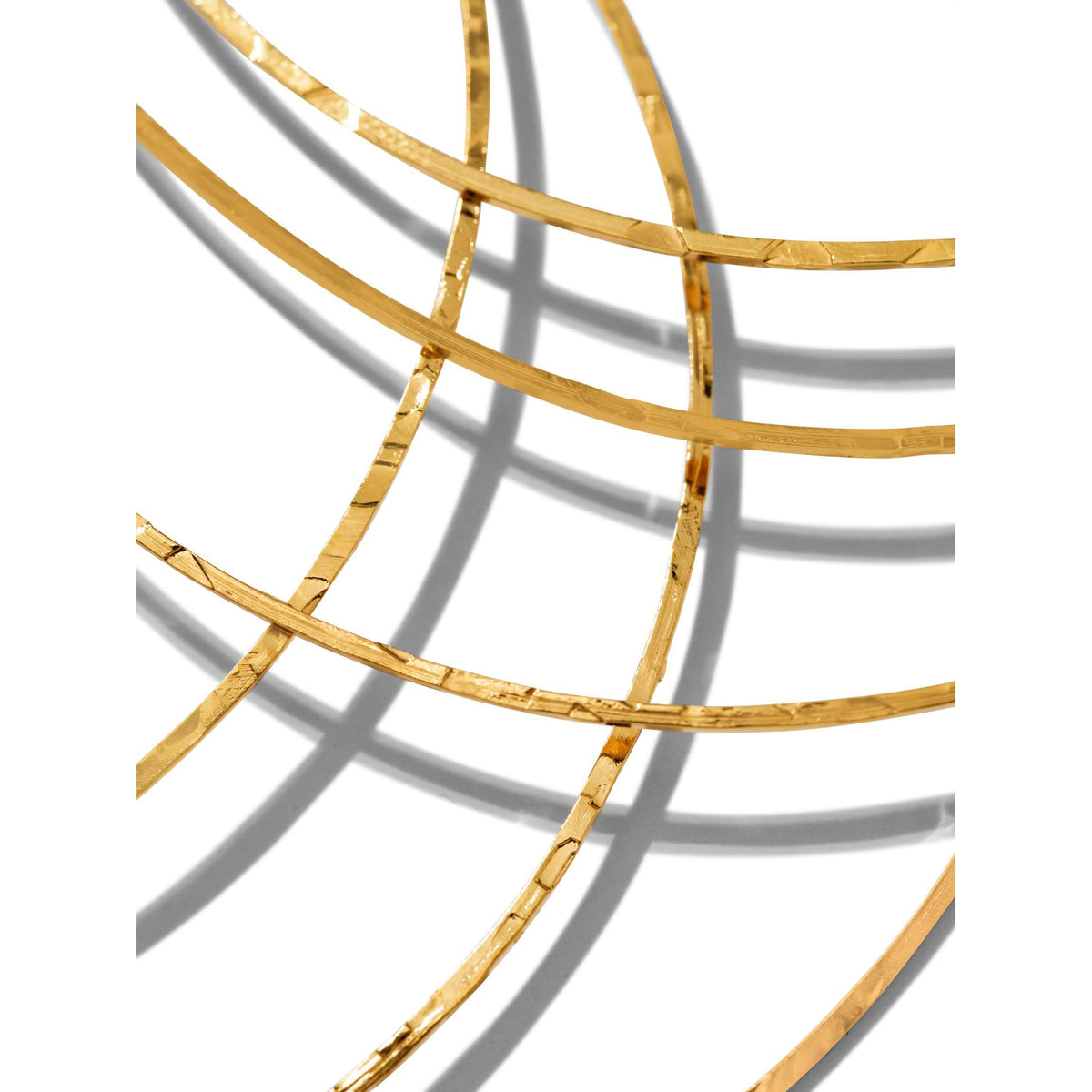 The Gold Triple Halo Hoop Earrings by JAREDJAMIN Jewelry Online feature thin, lightweight textured hoops of plated brass overlapping diagonally, casting soft, looping shadows for an abstract, minimalist display.