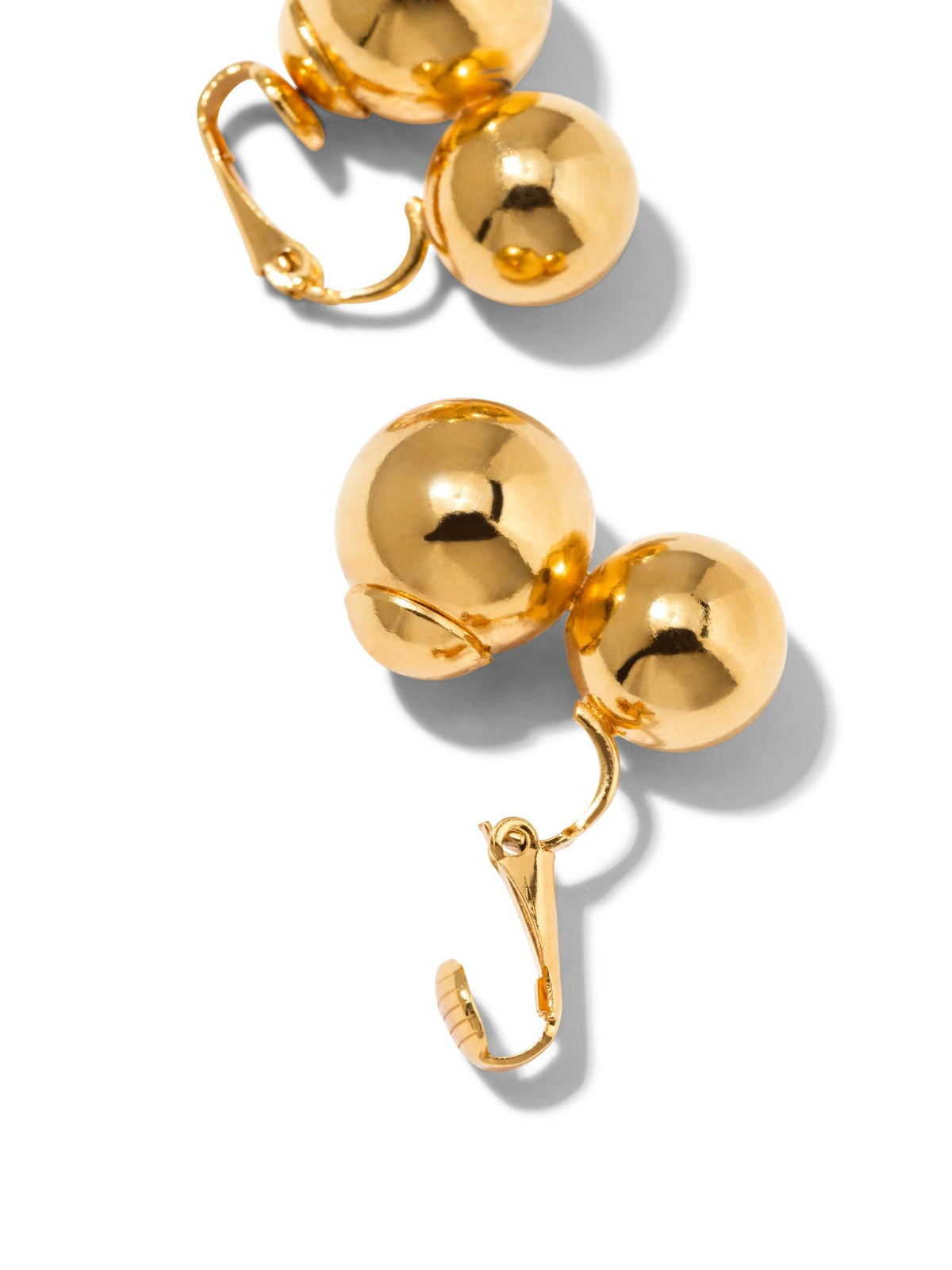 Les or Uptown Orbita Clip On boucles d'oreilles de JAREDJAMIN Bijoux en Ligne are shown against a fond blanc. Each 18K plaqué or boucle d'oreille features two connected metallic spheres, curved hooks, et clasp closures, casting soft right shadows.
