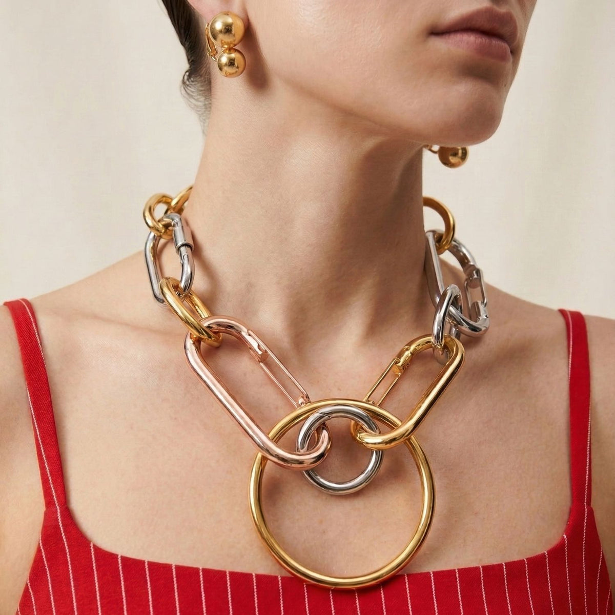 oro Uptown Orbita Clip On pendientes de JAREDJAMIN Joyería Online, con a audaz, vintage-inspired design y elegante oro finish, are worn by a woman en un red striped top.