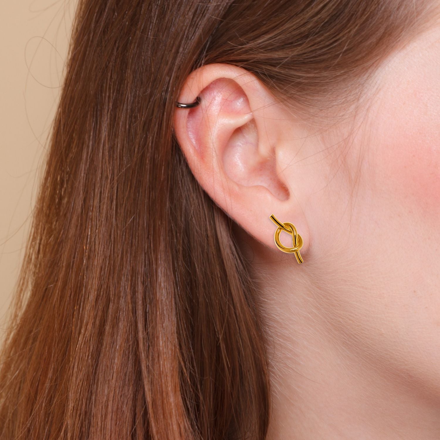 Gold Why Knot Stud Post Earrings by JAREDJAMIN Jewelry Online feature elegant knot-shaped designs in 18K gold plating, with a smooth, polished finish that highlights their sophisticated style.
