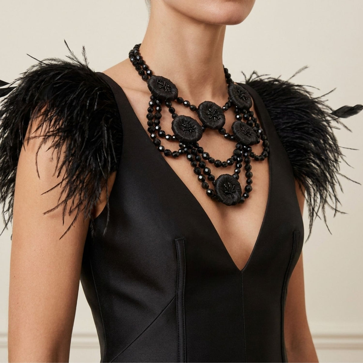 Front portrait of a female model wearing a sleek black dress with feathered shoulders, perfectly styling the 16-inch Good Mourning Victoria Necklace to demonstrate the dramatic 5-inch beaded bib drop resting beautifully on the chest.