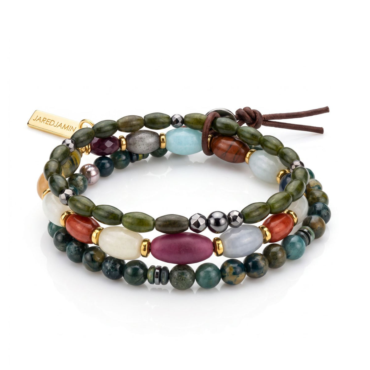 High-resolution studio product shot of the Silvan 3-piece men's stretch bracelet set resting flat, showcasing the gold logo tag and the complete multi-strand composition.