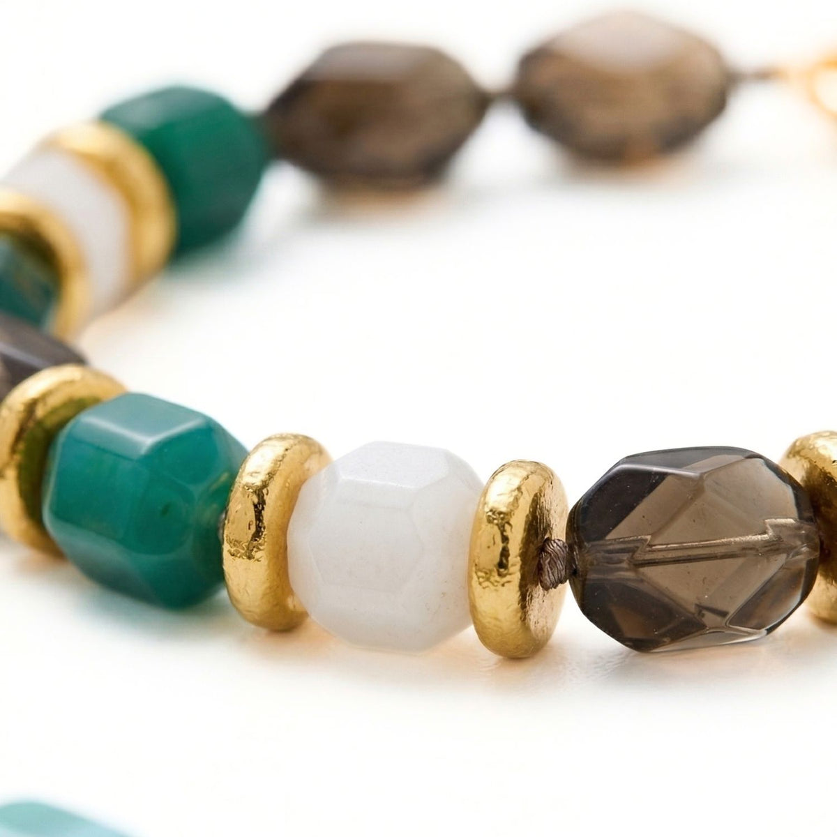 A close-up of our hand-assembled Green Dream Necklace: faceted green, white, and smoky brown beads are precisely punctuated by 18k gold-plated spacers on a slender cord. Small-batch, eco-conscious craftsmanship from our West Hollywood studio. Style Note: refracts under crisp shirting or layered evening knits.
