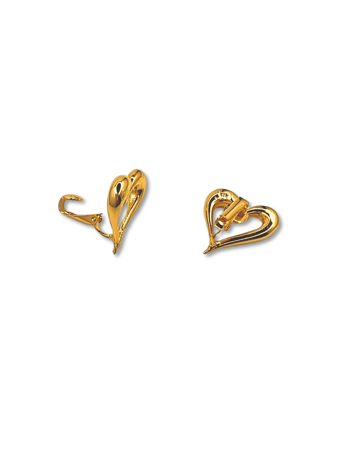 The Heartfelt Earrings by JAREDJAMIN Jewelry Online are shown with one front-facing and the other side-view, highlighting the clip-on closure. The gold heart-shaped design is simple yet elegant, with smooth, shiny surfaces on a white backdrop, embodying timeless romance.