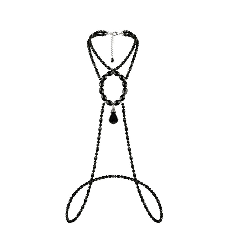 Flat lay on a white background of the Hera body necklace: multiple strands of small faceted black beads, a large oval ring of bigger faceted black beads, a black crystal teardrop pendant hanging from the ring's center, and long beaded strands looping below to wrap around the torso.