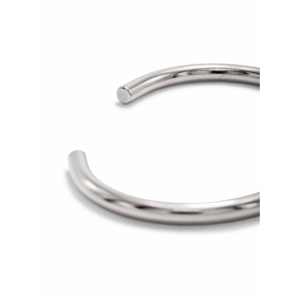 A close-up of the JAREDJAMIN Jewelry Online Silver Tubular Cuff shows its smooth, shiny, open-ended silver-plated design with flat ends—perfect for modern stacking against a white background.