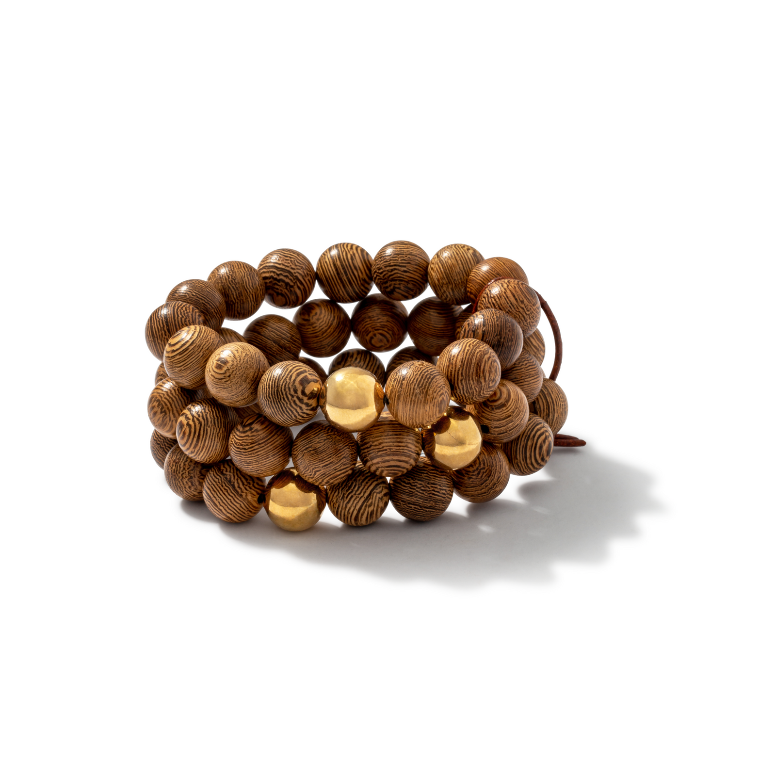 The Into The Woods Bracelet from JAREDJAMIN Jewelry Online features three coiled strands of round, patterned sandalwood beads with 18K gold accents, displayed on a white background with a soft shadow to the right.