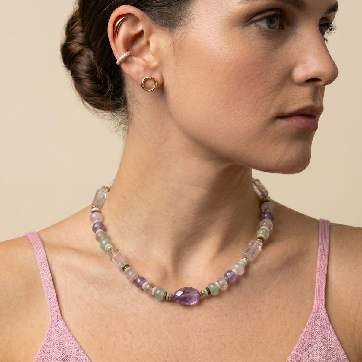 Styling view of a model wearing the JAREDJAMIN Iris Gemstone Necklace, a one-of-a-kind piece featuring a large amethyst protection stone, soft rose quartz beads, and natural healing crystals arranged along a 16-inch neckline.