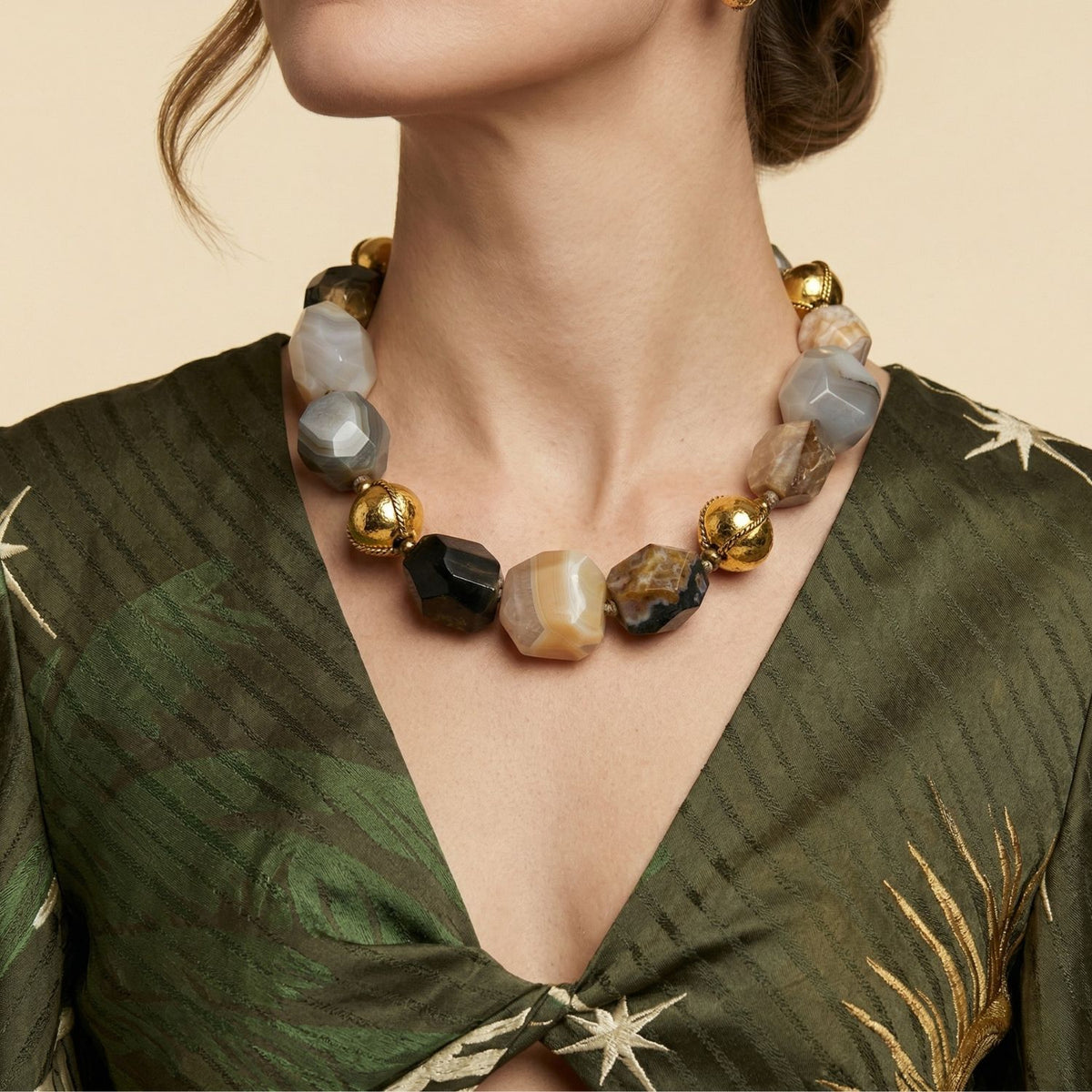 modelo usando the Isolde Agate collar styled con a green dress, showcasing the 19-inch (48 cm) length y the audaz, sculptural presence of the large faceted piedra preciosa beads.