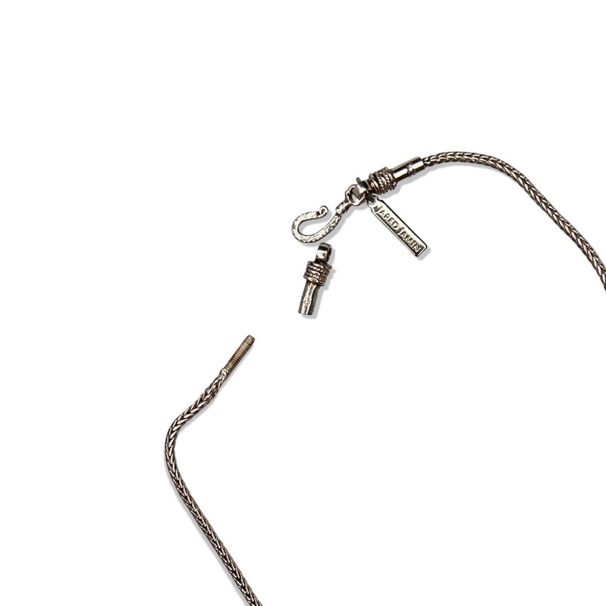 The Confidence Boost Necklace by JAREDJAMIN Jewelry Online is a sterling silver chain with a snake-like texture, featuring a hook clasp with branded tags and a tapered metal tip, displayed on a white background.
