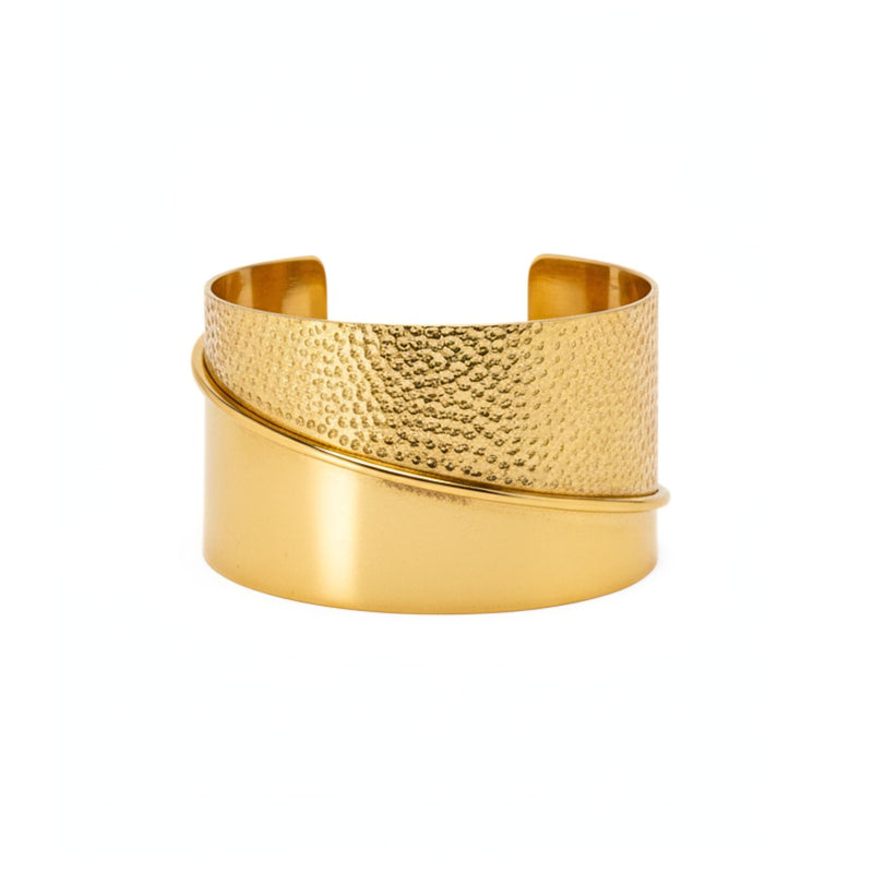 The Tribella Gold Cuff Bracelet by JAREDJAMIN Jewelry Online is a one-size 18K gold cuff with a wide band, featuring a hammered upper section, polished lower section, and diagonal raised line, open at the back and shown on a white background.