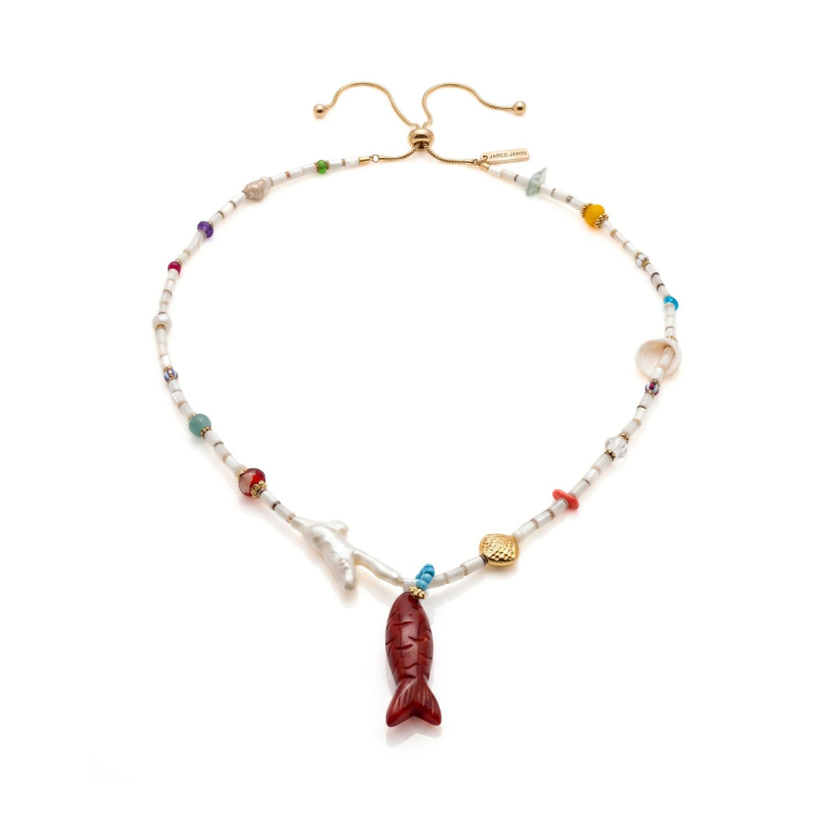 Studio product shot of the full Marisol Adjustable Necklace laid flat on a white surface, displaying the sliding golden elevator clasp chain at the top, the natural shells and coral-shaped pearls along the sides, and the Red Jasper fish pendant at the bottom.