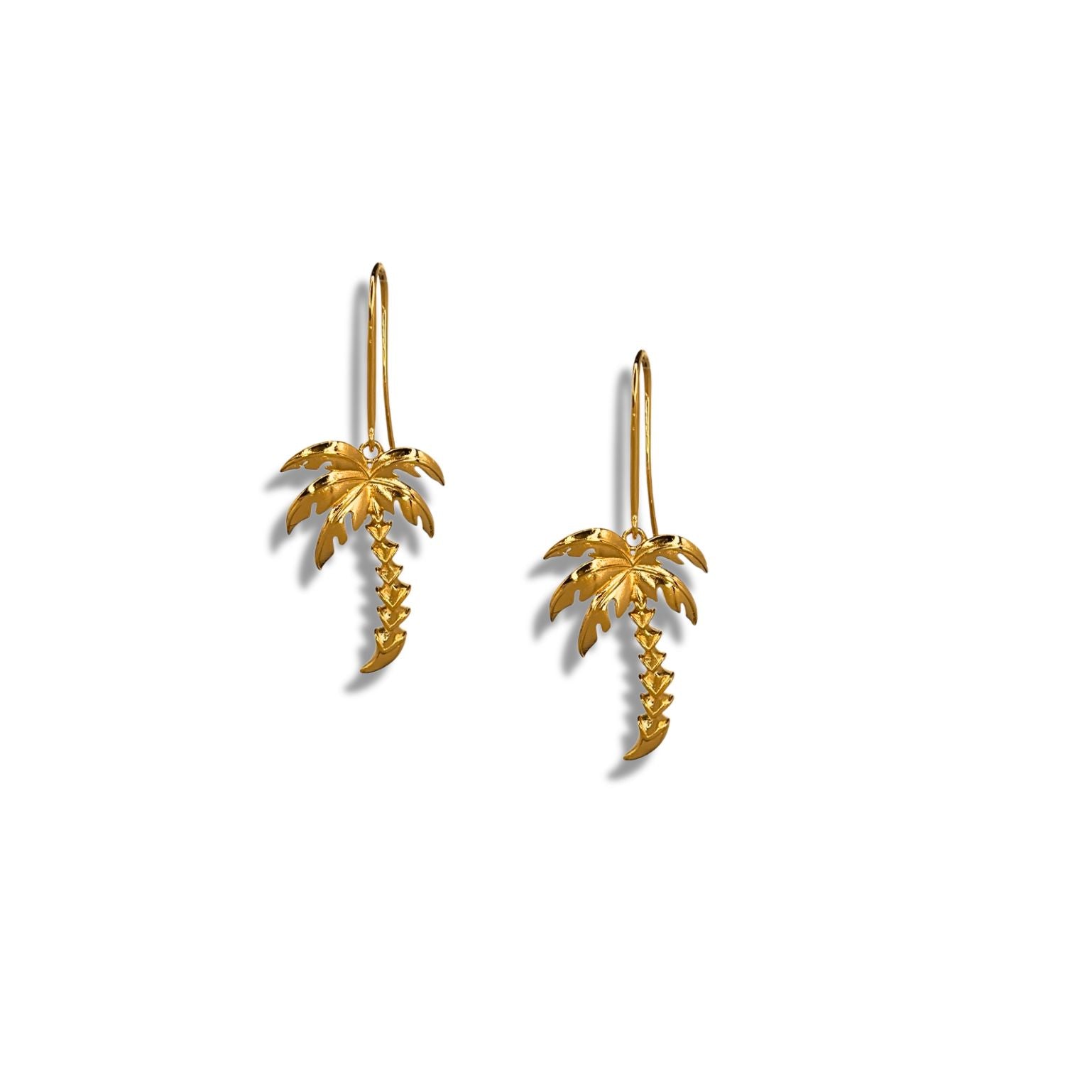 Two Gold Angeleno Palm Hook Earrings by JAREDJAMIN Jewelry Online are shown on a white background. Each earring has a detailed trunk and fronds with a hook, evoking a tropical vibe. Shadows below suggest the earrings are slightly elevated.