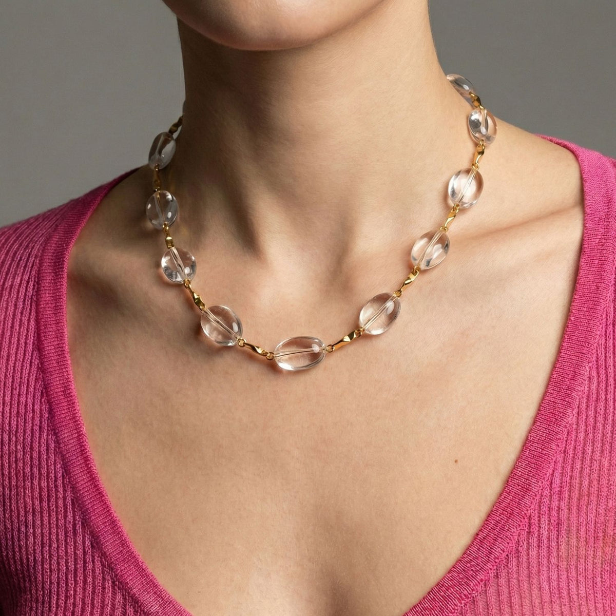 Un person wears the Arctic oro Bar-Link collar de JAREDJAMIN Joyería Online, styled con a pink V-neck knit top. Los image highlights their neck y upper chest against a neutral background.