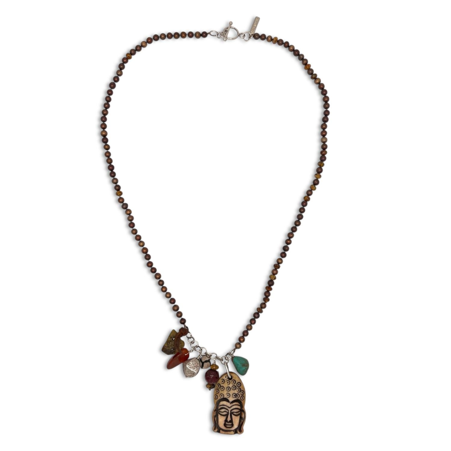 The Buddha Meanderings Beaded Necklace by JAREDJAMIN Jewelry Online features a light brown Buddha head pendant with dark accents and five jasper stone charms in red, green, and brown on silver loops, finished with a simple silver clasp.
