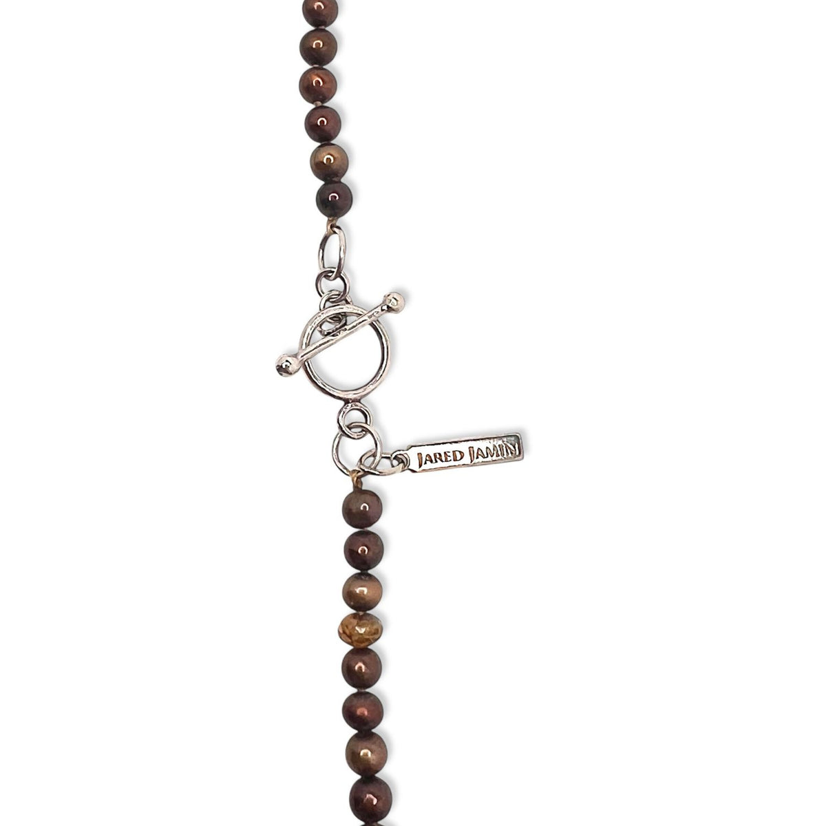 Un primer plano of the Buddha Meanderings Beaded collar de JAREDJAMIN Joyería Online features round brown jasper beads y a plata toggle clasp con a branded tag, set against a fondo blanco that highlights its intricate details.