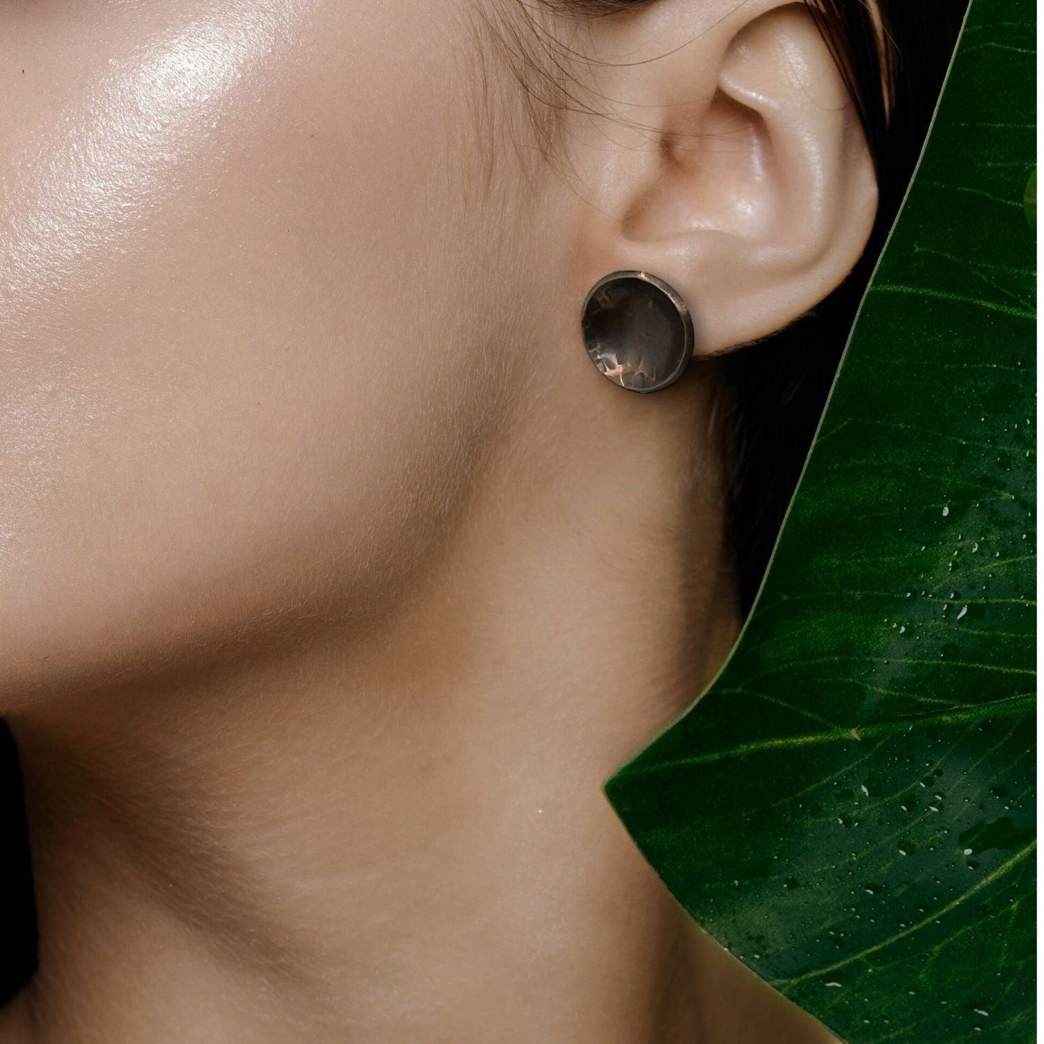 The Buttercup Antique Textured Stud Post Earrings by JAREDJAMIN Jewelry Online feature a round, dark metallic look with hammered and abstract geometric textures, shown on a white background casting soft oval shadows.