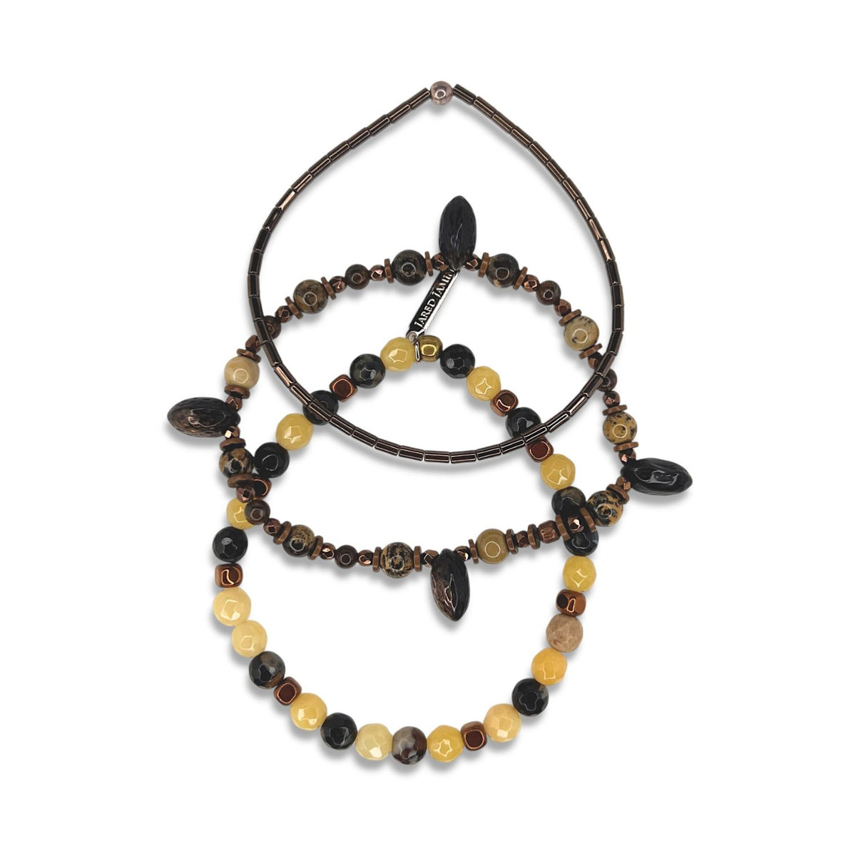 The Coconino Bracelet Set by JAREDJAMIN Jewelry Online features three beaded bracelets in a vertical row, with round and oval beads in brown, black, and yellow plus hematite accents for unique style variety.