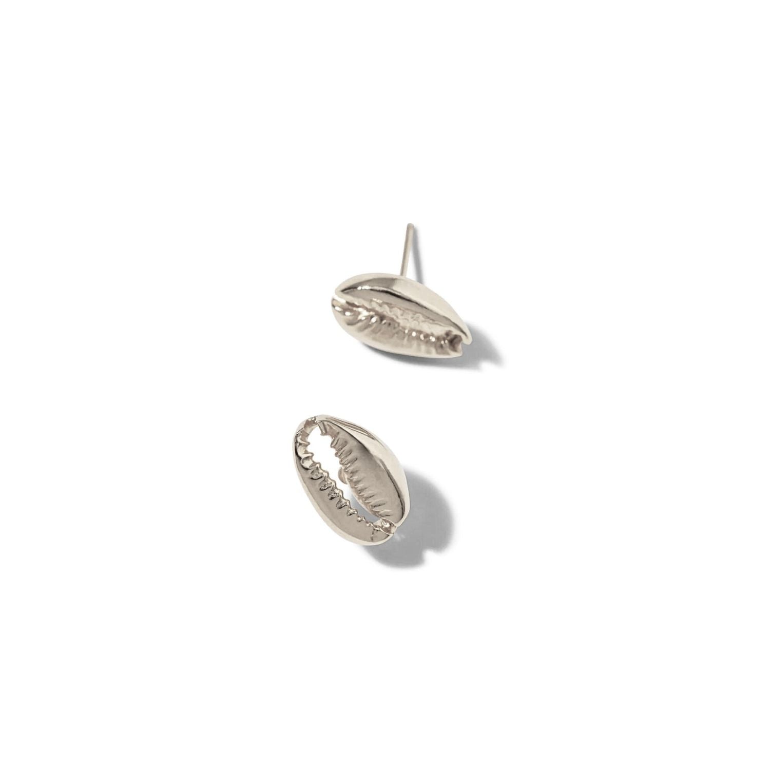 JAREDJAMIN Jewelry Online's Silver Cowrie Stud Post Earrings are shaped like cowrie shells. Shown on a white background, one lies flat to reveal its ridged opening while the other angles upward, showcasing this unique coastal-inspired design.