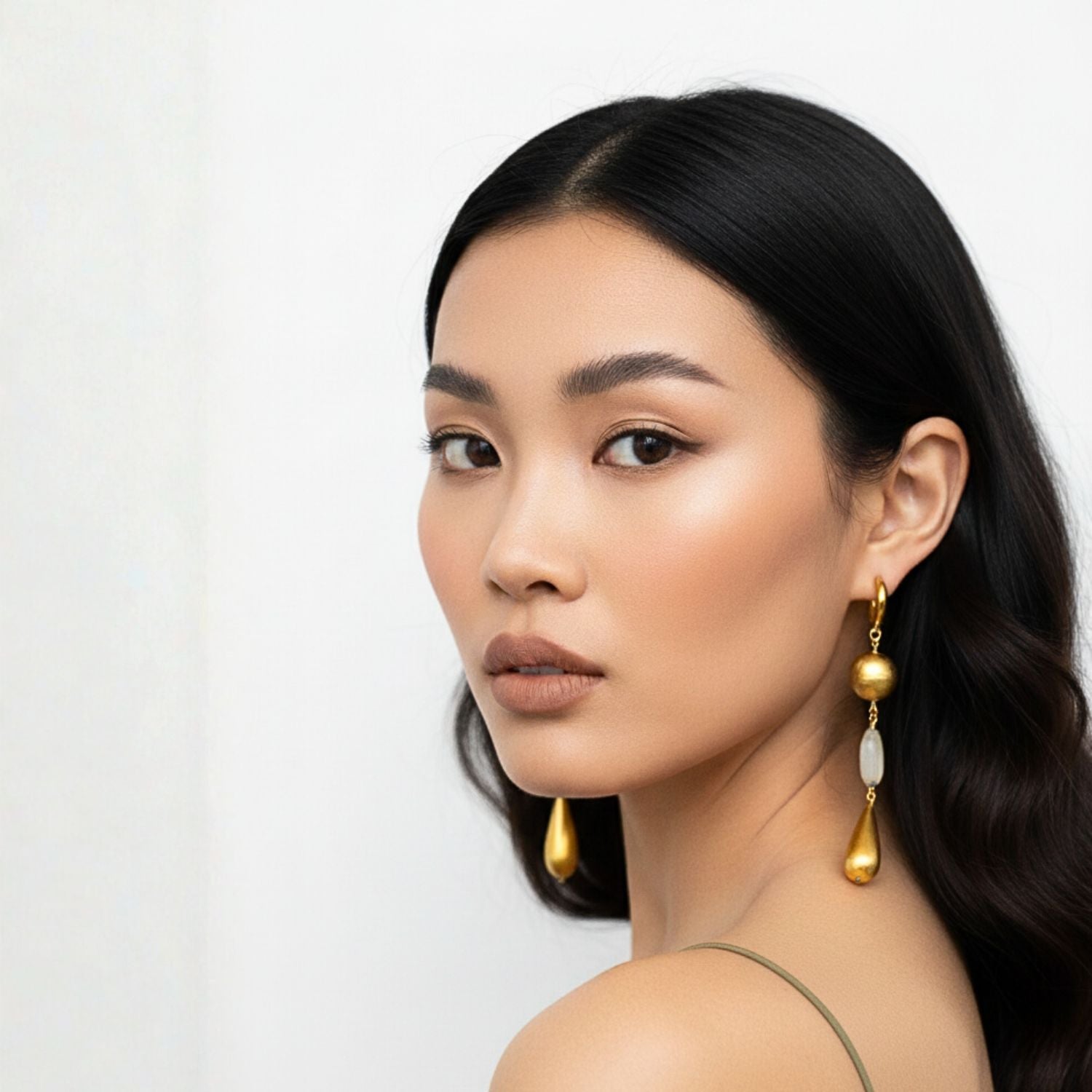 The Elegant Gypsy Earrings by JAREDJAMIN Jewelry Online feature gold-toned hoops, an oval gold bead, pale green rutilated quartz, and a long gold teardrop bead aligned on a wire. White background.