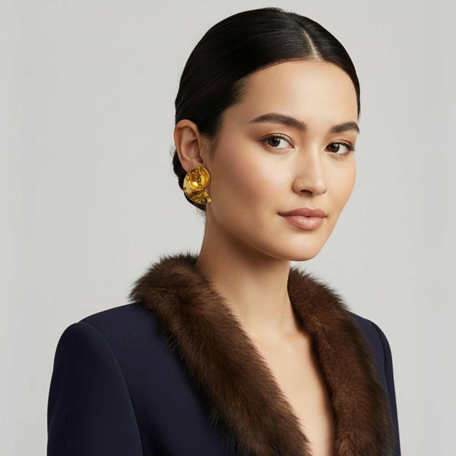 The Espiral Clip Earrings by JAREDJAMIN Jewelry Online feature an architectural spiral design in 18K gold plating, with a slightly hammered texture and elegant curves, inspired by modern art. Photographed on a plain white background.