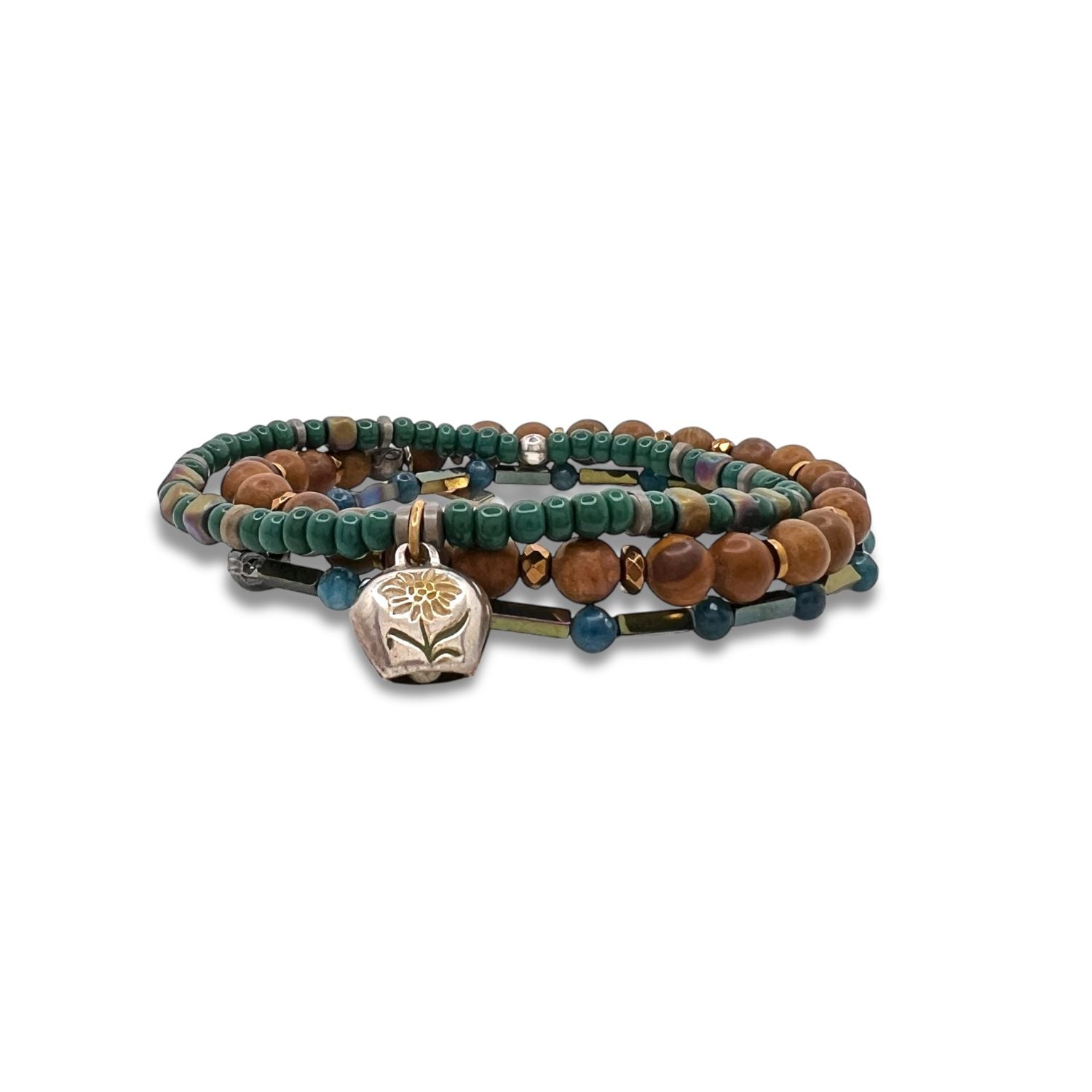 The Everest Foothill Bracelet Set by JAREDJAMIN Jewelry Online features layered turquoise, teal, and Tiger Skin Jasper beads with a silver lotus charm, coiled in a circle and displayed on a white background.