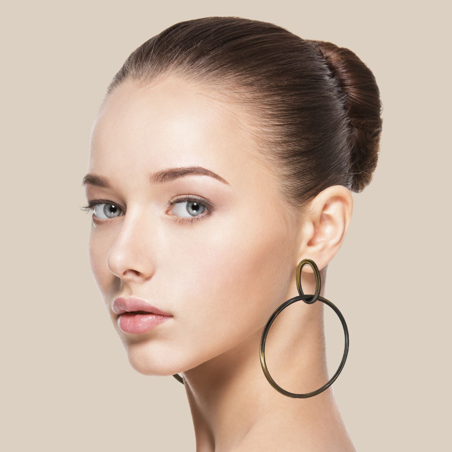 The Everly Antique Dangle Hoop Post Earrings by JAREDJAMIN Jewelry Online feature thin, shiny bronzed metal loops—one large and one small—creating a minimalist, bohemian look against a white background.