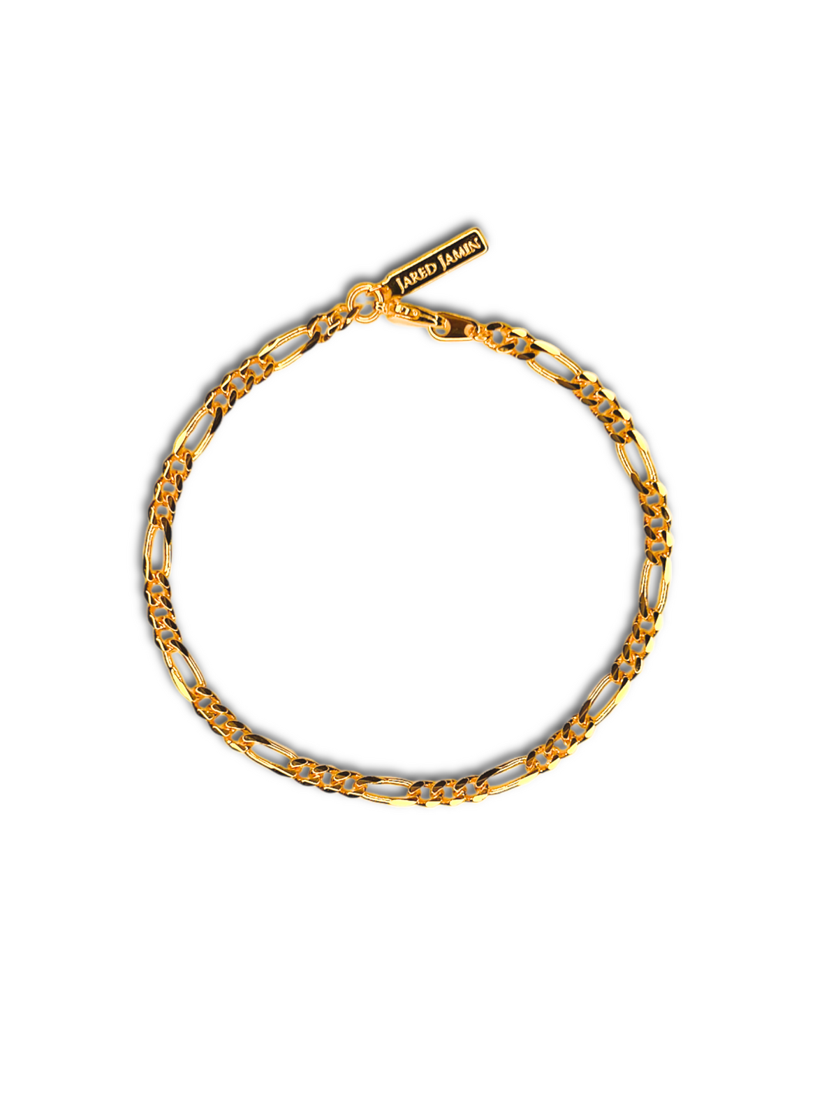 The Gold Finley-Figaro Chain Bracelet from JAREDJAMIN Jewelry Online is an 18K gold plated link chain with shiny oval links and intricate detailing. It features a small rectangular charm engraved with &quot;VAKKI JAMES&quot; and is secured by a lobster clasp in a circular shape on a white background.