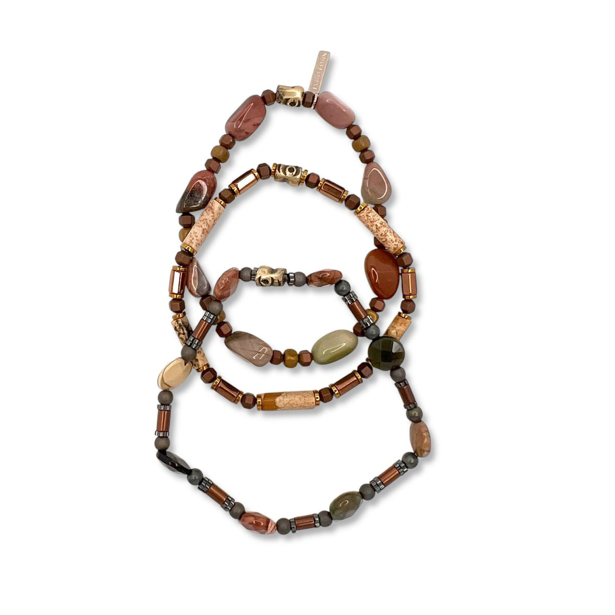 The Forest Floor Bracelet Set by JAREDJAMIN Jewelry Online features three beaded bracelets of multi-matte hematite and fancy jasper in earthy browns, tans, reds, and greens. Smooth and irregular beads evoke a woodland wanderer style on a white background.
