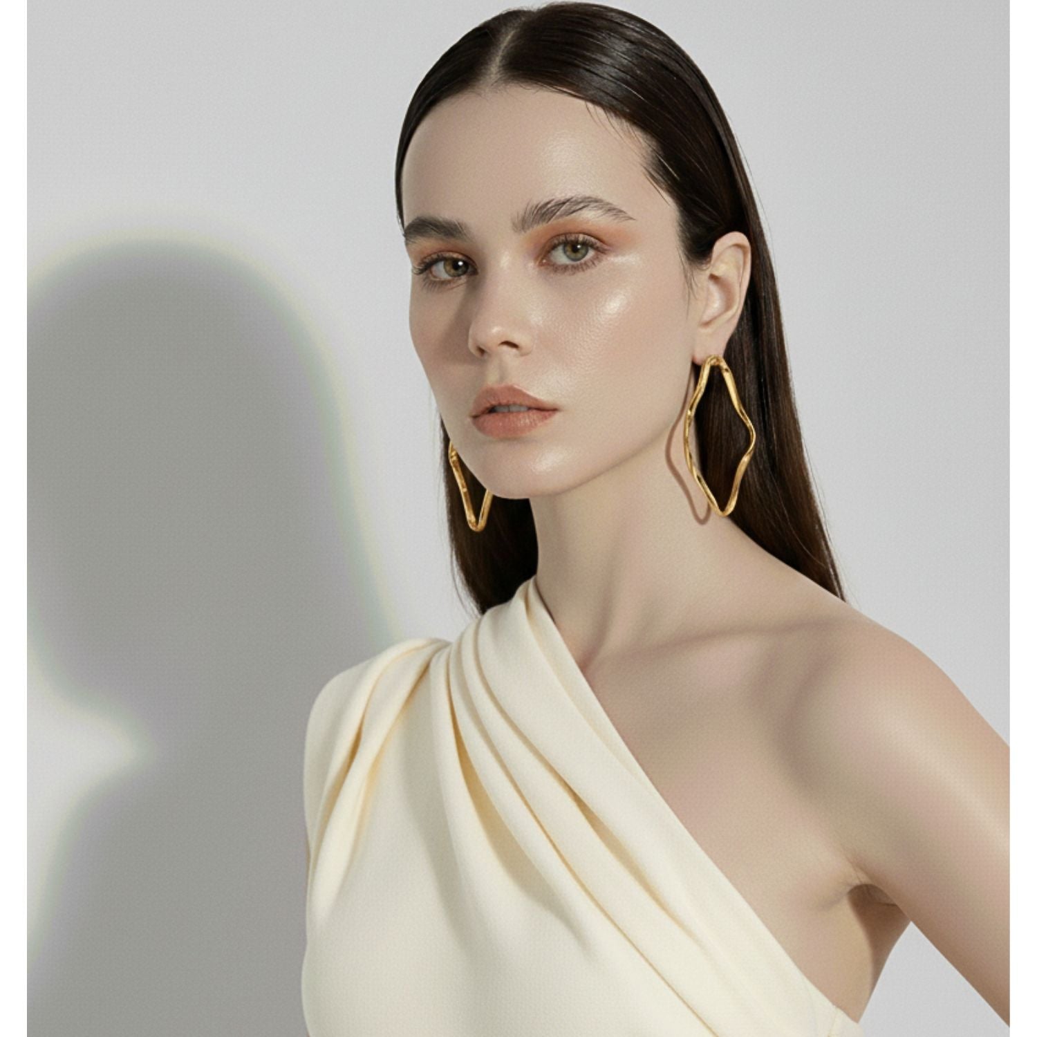 Two Gold Ribbonelle Post Earrings by JAREDJAMIN Jewelry Online, featuring hand-crafted wavy square shapes and shiny 18K gold plating, are displayed on a white background for a distinctive modern look.