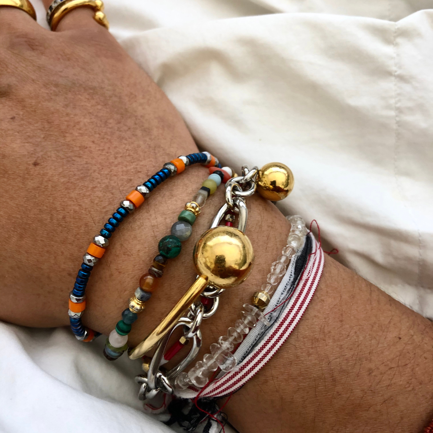 The Gold Orbita Bracelet by JAREDJAMIN Jewelry Online is an 18K gold-plated piece with a polished finish, featuring two textured orbs—one large and one small—at each open end.