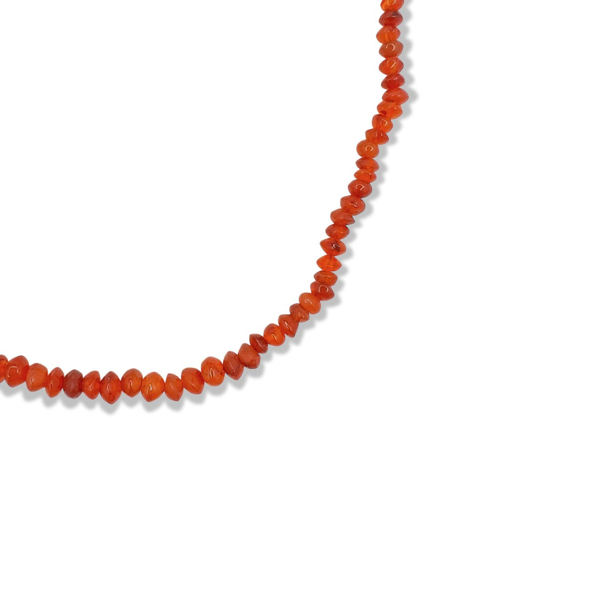 A partial view of the Gemstone Trail Carnelian Necklace by JAREDJAMIN Jewelry Online shows small, polished, oval red-orange beads closely arranged in a curve on a white background. Carnelian is prized for its beauty and energizing properties.
