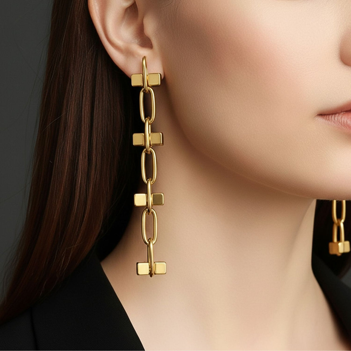 Close-up of a woman wearing JAREDJAMIN Jewelry Online’s Gold Blockbuster 4 Block Earrings—modern, geometric 18K gold plated dangles with linked rectangular and bar shapes. She has straight brown hair and a black blazer, set against a dark background.
