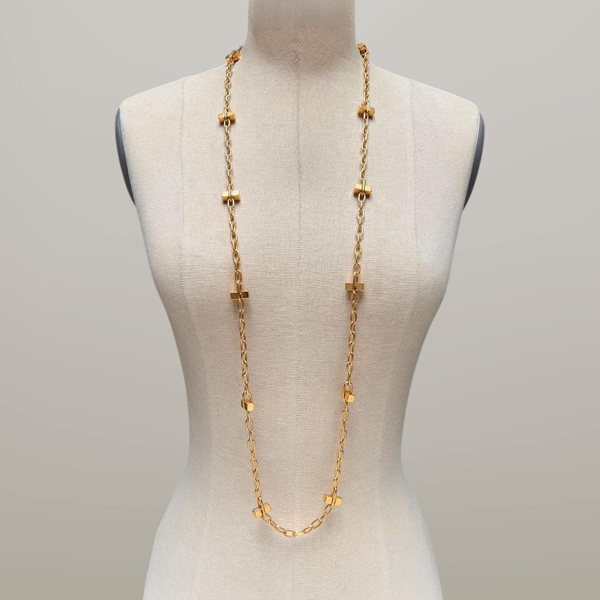 Los JAREDJAMIN Joyería Online oro Blockbuster Lite Long collar features 18K bañado en oro rectangular links y small oro accents, exhibido sobre a beige dress form against a light gray background. Secures con a lobster clasp.