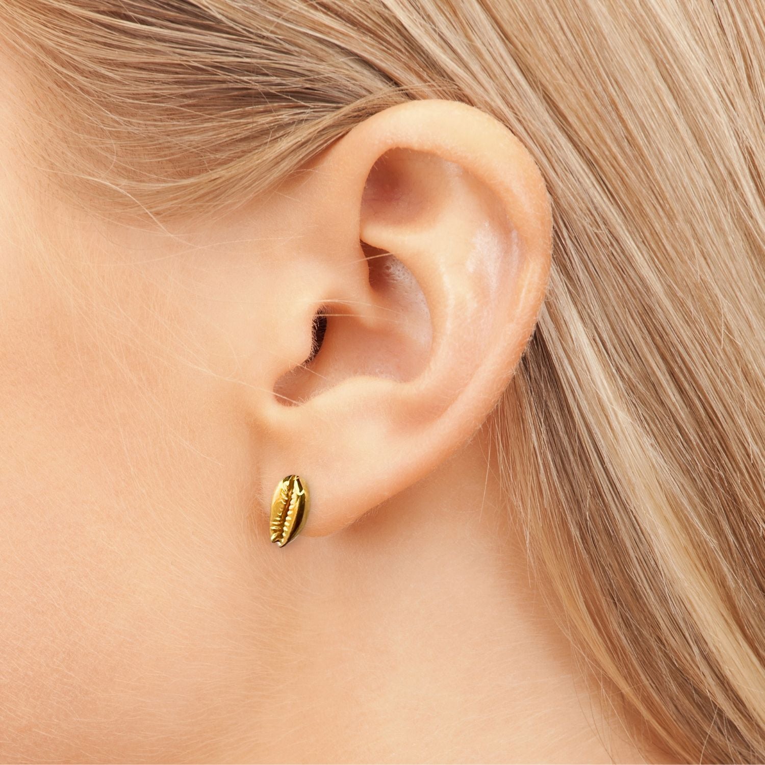 The Gold Cowrie Stud Post Earrings by JAREDJAMIN Jewelry Online feature shiny 18K gold plating and a cowrie shell design, shown side by side on a white surface with soft gray shadows for a true summer vibe.