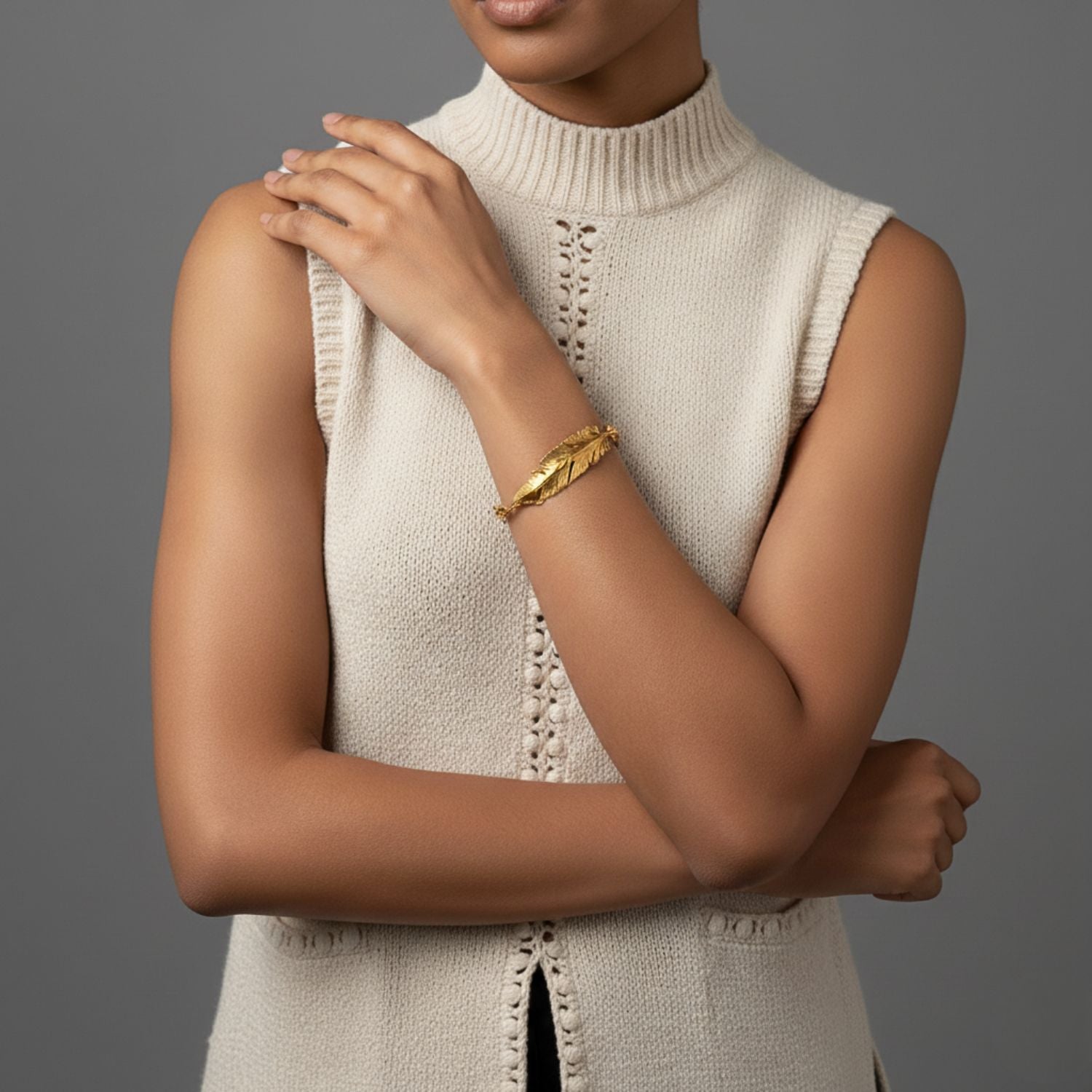 The Gold Feather Plume Bracelet by JAREDJAMIN Jewelry Online features an oversized, detailed feather on a chunky chain with a small rectangular tag for a personalized touch, exuding whimsical elegance against a plain white background.