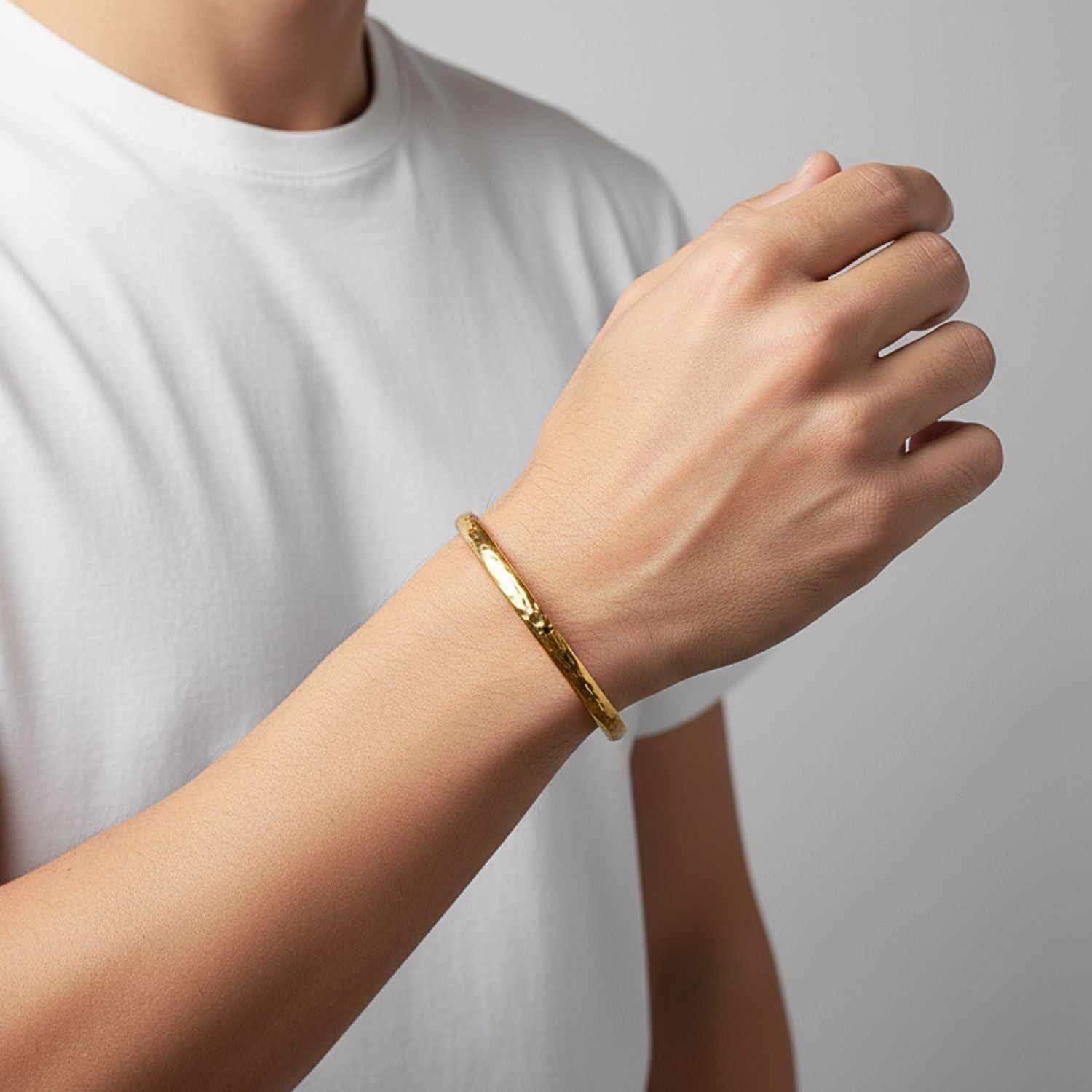 A close-up of the Gold Parker Textured Cuff by JAREDJAMIN Jewelry Online, an open-ended 18K gold plated bracelet with a hand-hammered finish, gleaming with a polished, minimalist elegance against a white background.