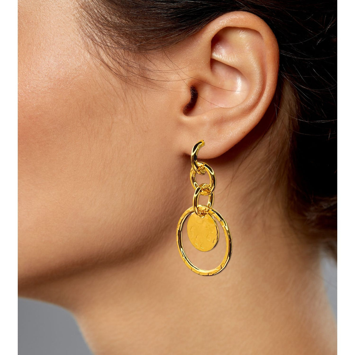 Close-up of a woman’s ear wearing JAREDJAMIN Jewelry Online’s Gold Peacock Preen Post Earrings, featuring 18k Gold Plate, a small hoop, a larger textured hoop, and an oval charm for an elegant, layered look.