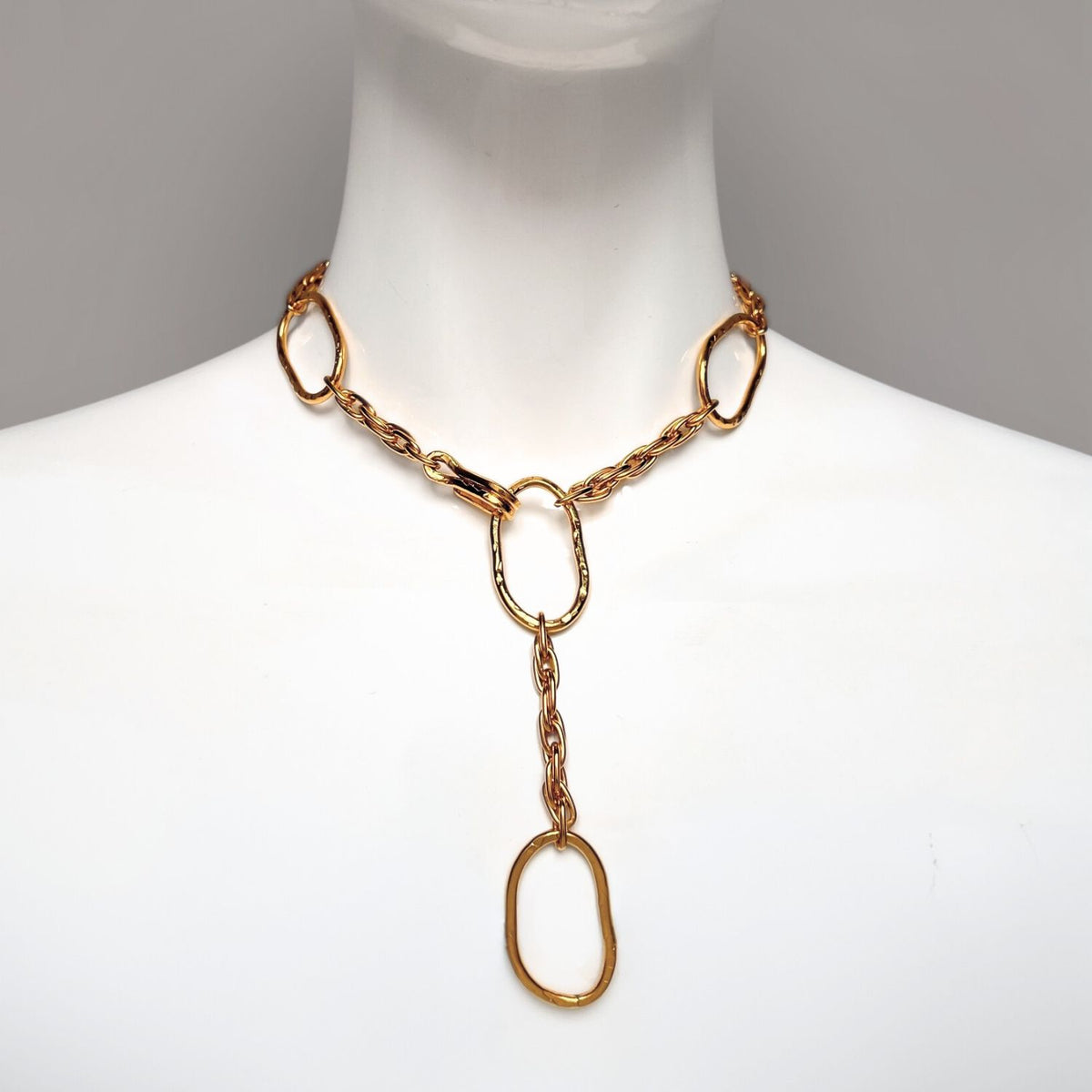 Displayed on a white mannequin is JAREDJAMIN Jewelry Online&#39;s Gold Shackle and Rope Link Necklace, featuring 18K gold-plated large, oval interconnected links in a Y-shaped drop for a stylish, minimalist design perfect for any occasion.