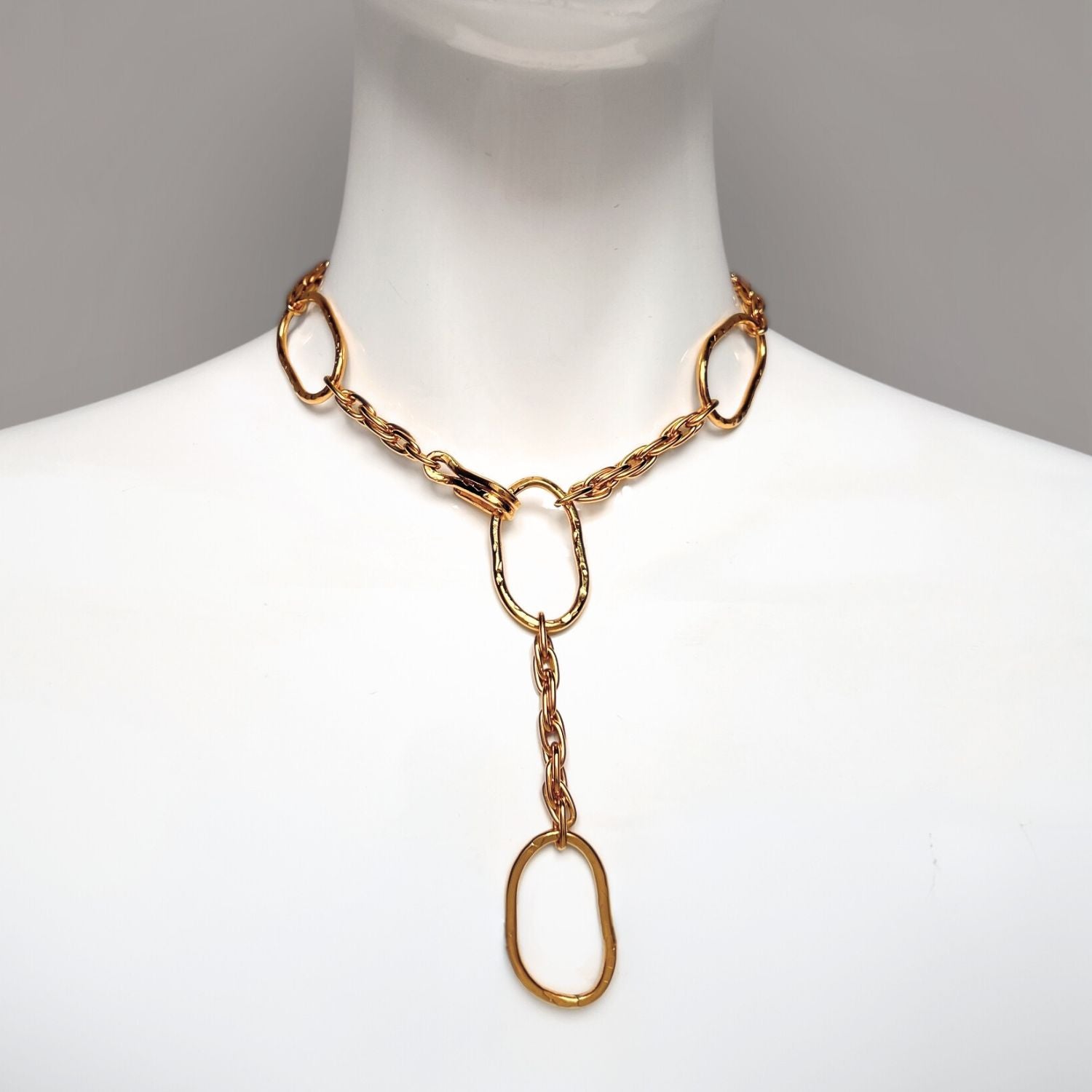 The Gold Shackle and Rope Link Necklace by JAREDJAMIN Jewelry Online features large, irregular oval-shaped links connected by smaller double chain links. An extended 18K gold plated chain dangles, creating a drop effect with a shiny finish and modern, elegant design.