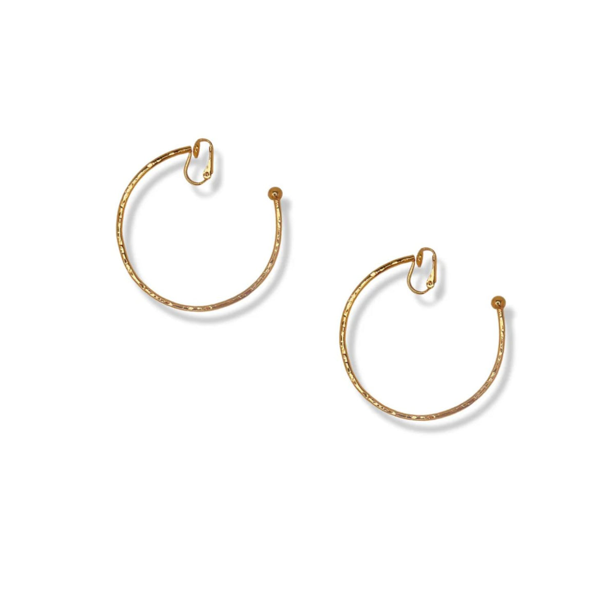 The Gold Small Hooptastic Clip On Hoop Earrings by JAREDJAMIN Jewelry Online are shown on a white background, featuring thin hammered open circles with small spherical ends and curved hooks for a subtle, elegant textured look.