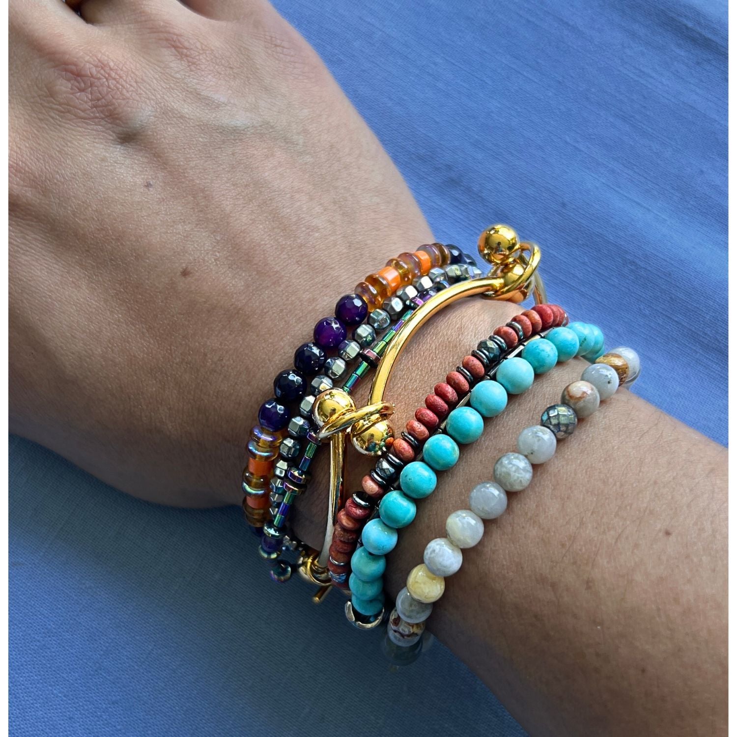 The Gold Smaller Orbita Nova Bracelet by JAREDJAMIN Jewelry Online features a smooth, round 18K gold-plated band with five spaced beads knotted in place, a toggle clasp, and a polished rectangular tag, shown against a white background.