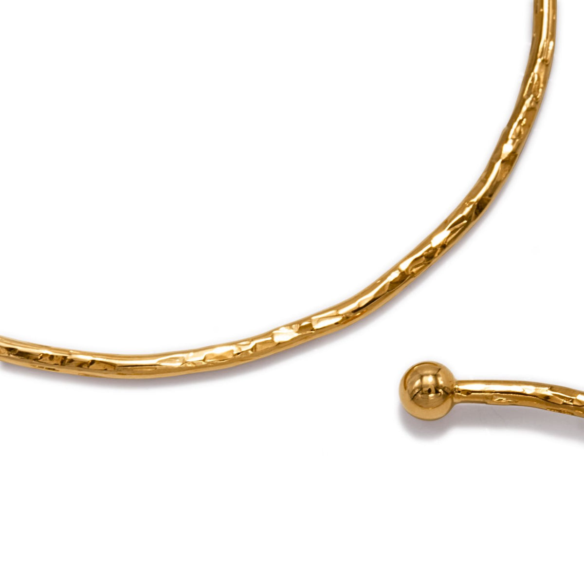 A close-up of the Gold Medium Hooptastic Clip On Hoop Earrings by JAREDJAMIN Jewelry Online shows their thin, textured, gold-colored surface with a hammered finish. Partially visible against a white background, their elegant sheen stands out.