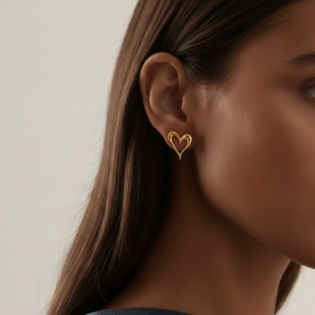 Un woman avec straight brown hair wears JAREDJAMIN Bijoux en Ligne’s Heartfelt boucles d'oreilles. Les focus on her face et ear against a neutral background highlights the romantic or heart-shaped bijoux et her smooth, clear skin.