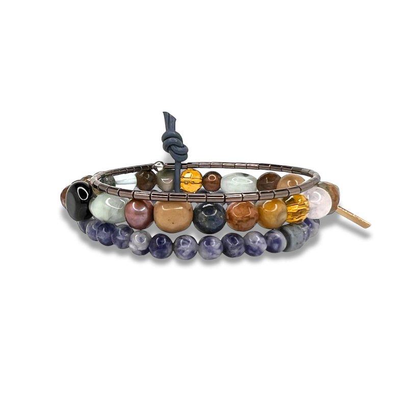 Los Maurice piedra preciosa pulsera Set de JAREDJAMIN Joyería Online features coiled elastic bands con round piedra preciosa-glass beads in black, brown, purple, yellow, pink, y blue. Un gray knot secures the design, finished con a small oro tag.