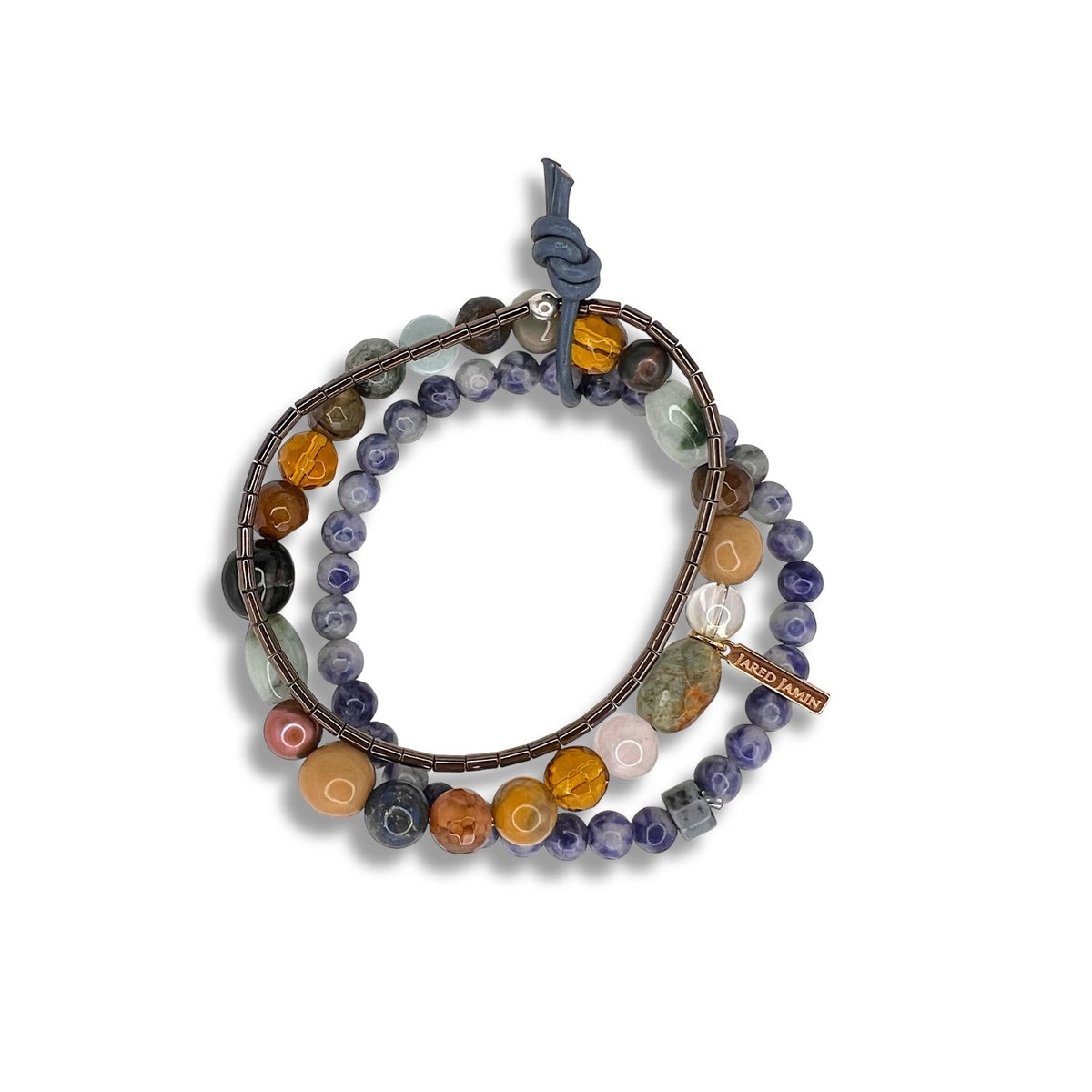 The Maurice Gemstone Bracelet Set by JAREDJAMIN Jewelry Online features coiled hematite with round multicolored beads, metallic tube accents, a blue knotted clasp, and a "LABRD HANDS" tag, displayed on a white background.