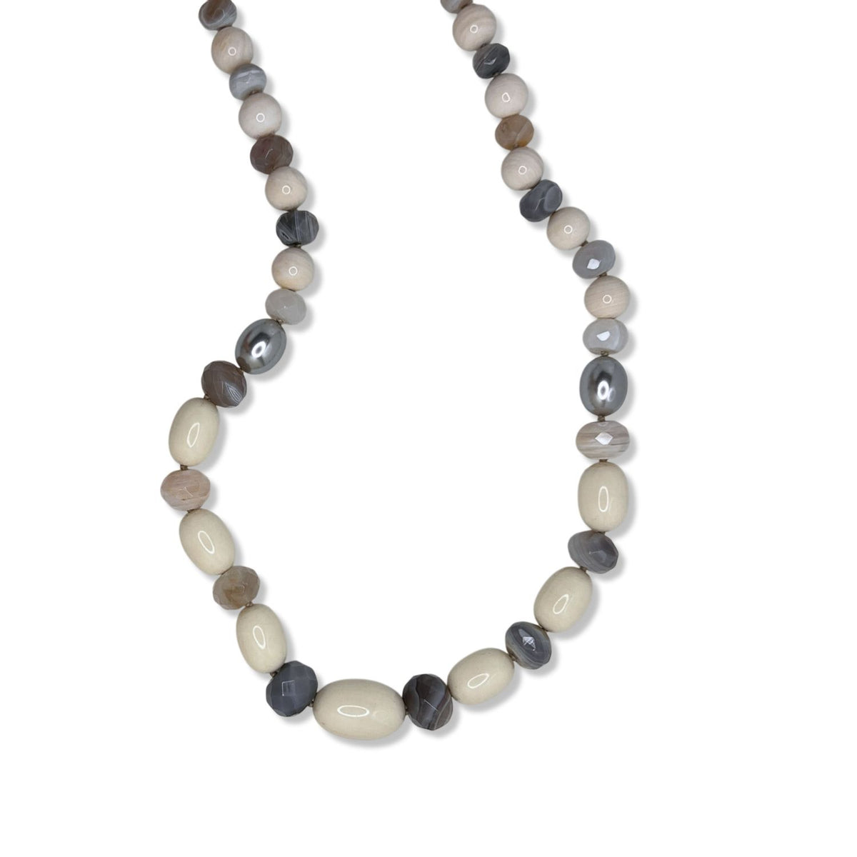 The Montana Quarry Necklace by JAREDJAMIN Jewelry Online features alternating oval and round agate beads in cream, beige, and gray—some faceted for shine—arranged in a curved shape against a white background.