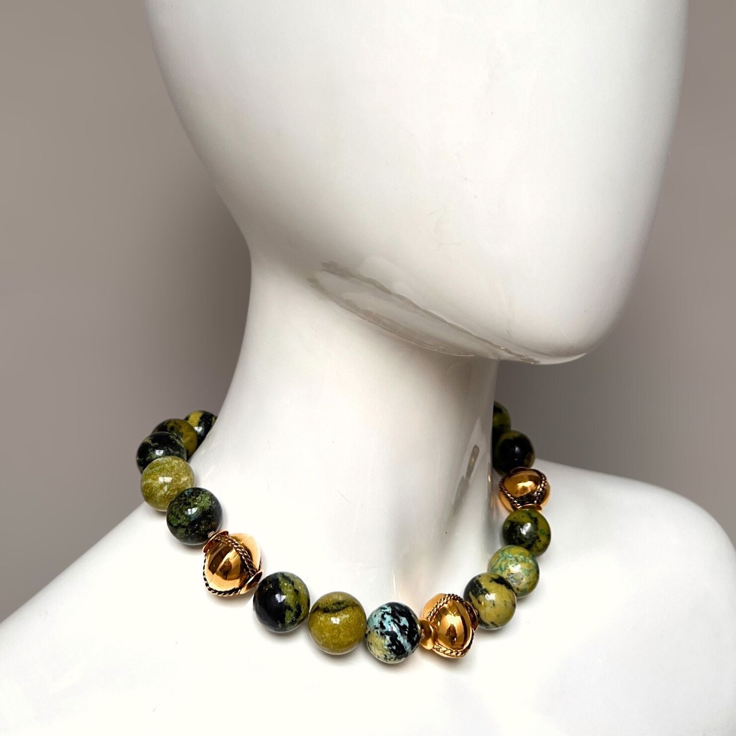 The Moss Maiden Necklace by JAREDJAMIN Jewelry Online features hand-knotted green moss agate and black marbled stones, accented with glossy gold beads. A spring ring clasp with an adjustable chain and a gold charm completes this elegant blend of natural and metallic elements.