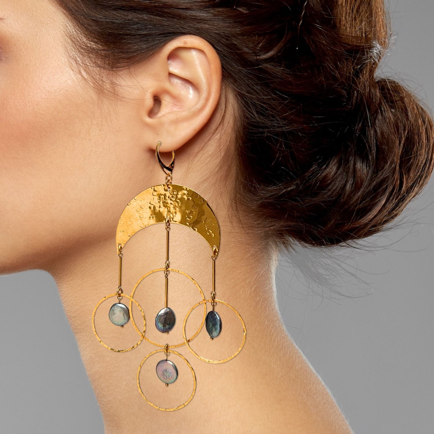 The Mystic Moon Pearl Chandelier Earrings by JAREDJAMIN Jewelry Online feature hammered 18K gold semi-circles with three hanging gold rings, each adorned with iridescent coin pearls for an elegant statement look.